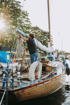Male on yacht works with rigging