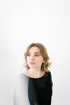 Woman in a black shirt models in front of a white wall with a distorted light reflection