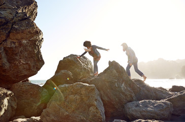 Mixed race couple climbing on rocks at the beach