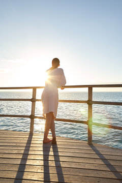 Woman looking at sunrise on ship deck