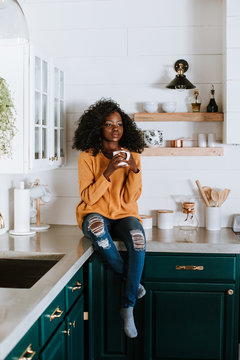 Woman Sitting on Kitchen Counter with Coffee Mug