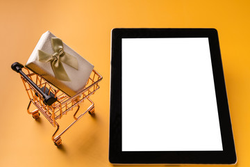 Shopping cart model and tablet on yellow background