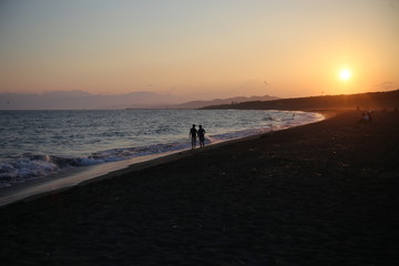 夕焼けの浜を歩くカップル