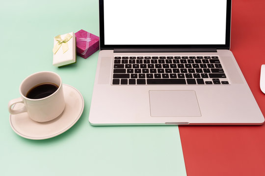 Coffee, laptop and gift box on red and green contrast background
