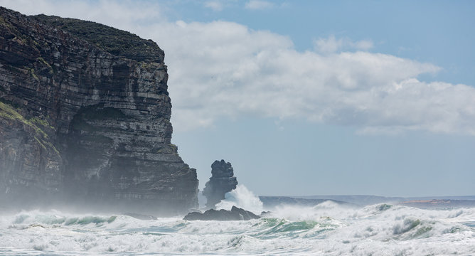 Surf and a sunlit cliff.