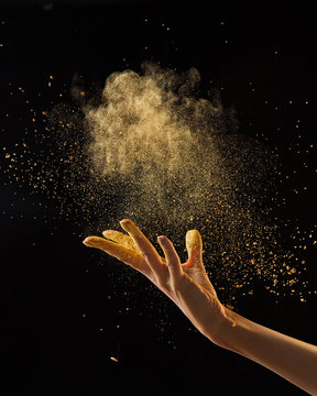 Beautiful photo of female hand throwing gold dust on a black background with copy space. Layout for your ideas.