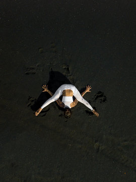 Woman doing yoga exercices on a black beach