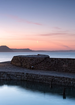 Moon rising over a stone jetty