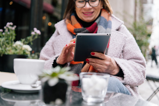 Cheerful lady browsing tablet in cozy outdoor cafe