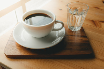 Hot cup of Americano coffee on wooden desk.