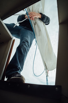 A man working to tie a mainsail down.