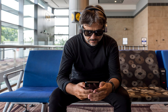 Man checking his phone while waiting on an airport