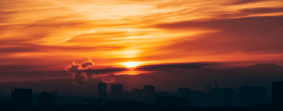 Panoramic city sunrise with polluting chimneys