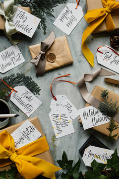 Gifts from Christmas decorated with mustar, sage and taupe velevt and silk ribbons and hand written tags with "Merry Christmas" spelt in multiple languages