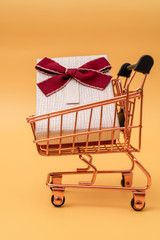 Shopping cart model with gifts on a yellow background