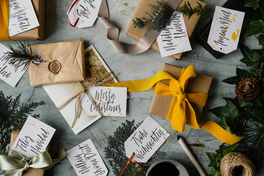 Handwritten tags with Merry Christmas written in several different languages and presents