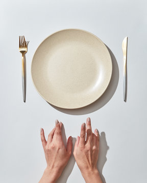 Waiting for dinner at the table, served empty dish and cutlery female's handon a white background, place for text. Top view.