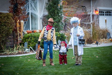 Group of kids dressed in Halloween costumes going trick or treating outdoors in October in a decorated neighborhood