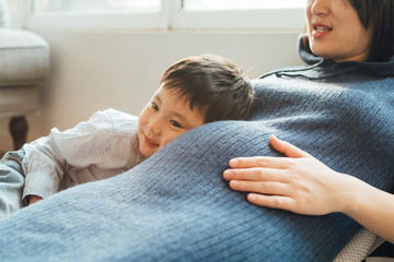 Young pregnant mother with son at home