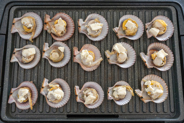Grilling scallops and cheese on electric pan at home