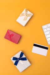 Gift, bank card and computer keyboard in front of a yellow background