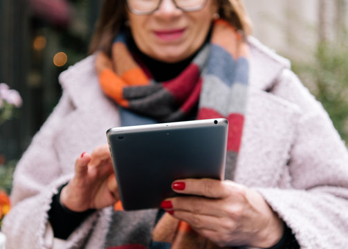 Cheerful lady browsing tablet in cozy outdoor cafe