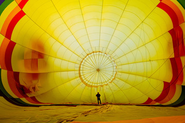 Fototapeta premium The interior of a yellow hot air balloon being inflated, with a person inside for scale