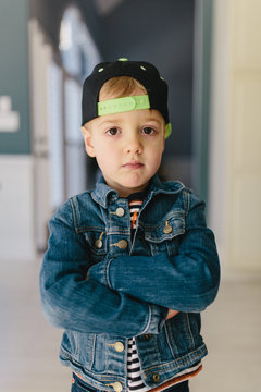 Portrait of a young boy wearing a denim jacket and a baseball hat backwards