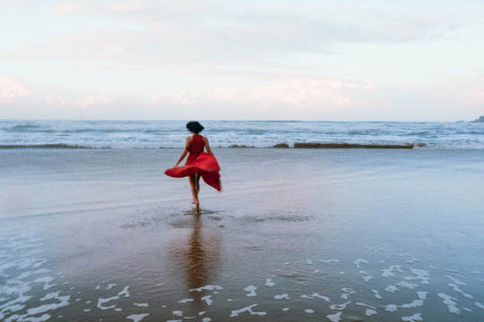 woman in red dress plays and feels freedom on the beach