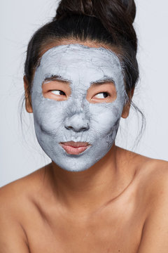 Fun young asian woman doing facial treatment