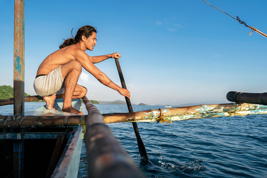 Cheerful man rowing on fishing boat