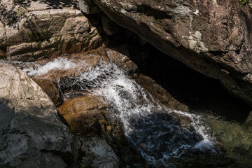 water running down the rocking creek between giant rocks in the forest