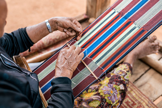 Close up of elderly woman weaving on street