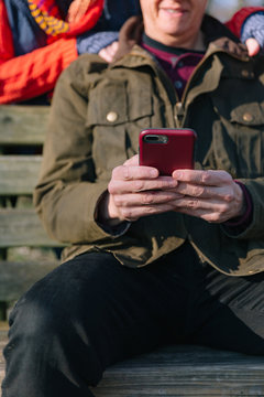 Close up of a man's hands as a mature couple in their sixties using a mobile phone.