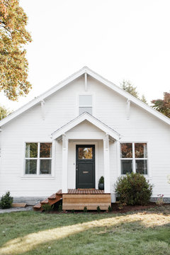 White home with black front door and wooden porch