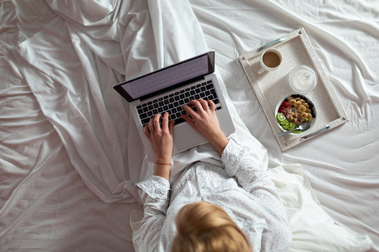 Woman lying in bed using her laptop