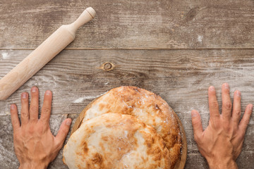 cropped view of man near wooden table with lavash bread and rolling spin