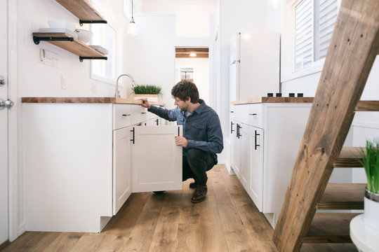 Home: Man Looking Inside Cabinet For Something