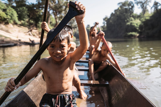 Naklejki Asian kids paddling on boat in the middle of the jungle
