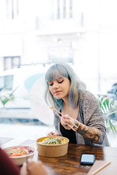 Stylish woman enjoying food in poke bowl cafe