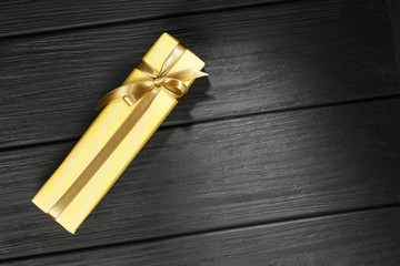 Gift box with ribbon on black wooden background top view.