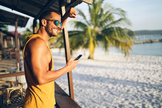 Cheerful man speaking on phone near shack