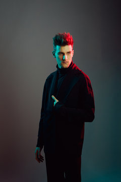 Young man wearing trench coat in studio.
