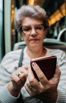 Blurred senior woman typing message on mobile phone in subway train