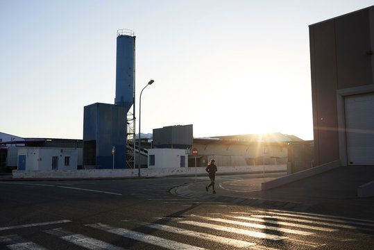 Female runner training industrial zone sunrise.