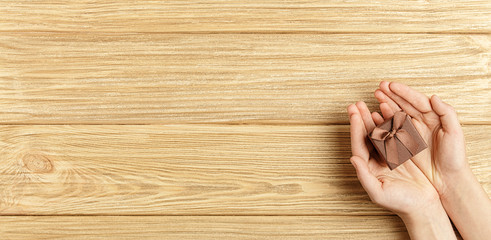 gift box in the hands on a wooden background top view