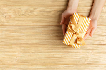 gift box in the hands on a wooden background top view