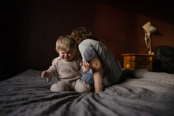 Baby girl with her mother crying on bed