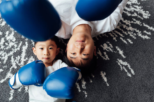 Portrait of father and son with boxing gloves lying on floor