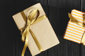 Gift box with ribbon on black wooden background top view.